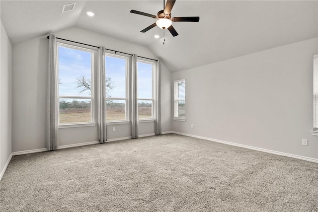 spare room with ceiling fan, vaulted ceiling, carpet flooring, and plenty of natural light