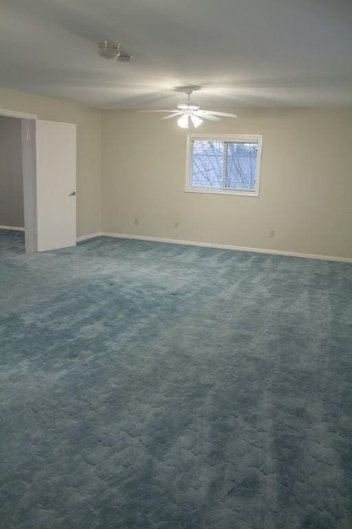 spare room with dark colored carpet and ceiling fan