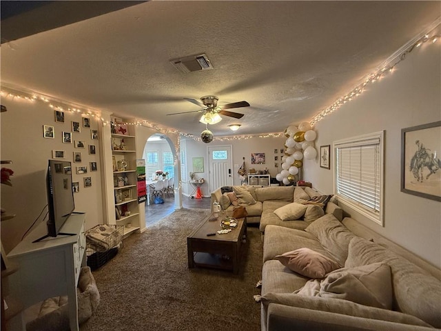 carpeted living room with ceiling fan and a textured ceiling