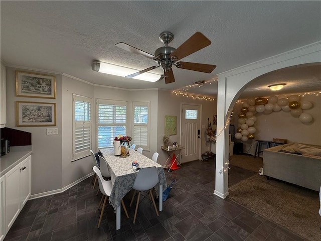 carpeted dining room featuring a textured ceiling, ceiling fan, and ornamental molding