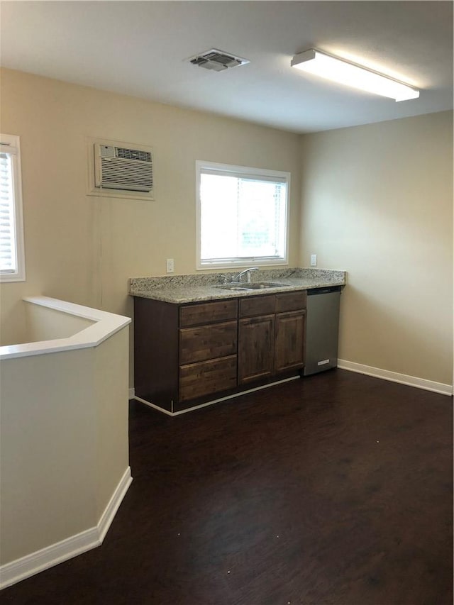 kitchen with dark brown cabinetry, sink, an AC wall unit, dishwasher, and dark hardwood / wood-style floors