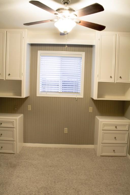 unfurnished dining area featuring ceiling fan, wooden walls, and carpet floors