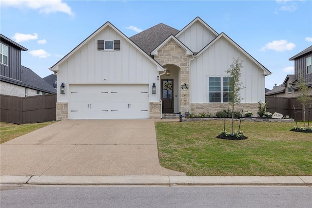 modern farmhouse featuring board and batten siding, a front lawn, fence, concrete driveway, and stone siding