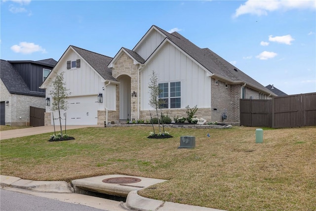 view of front of property featuring a front yard, concrete driveway, board and batten siding, and stone siding