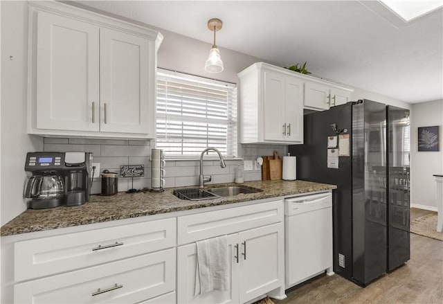 kitchen featuring a sink, white cabinets, freestanding refrigerator, decorative backsplash, and dishwasher