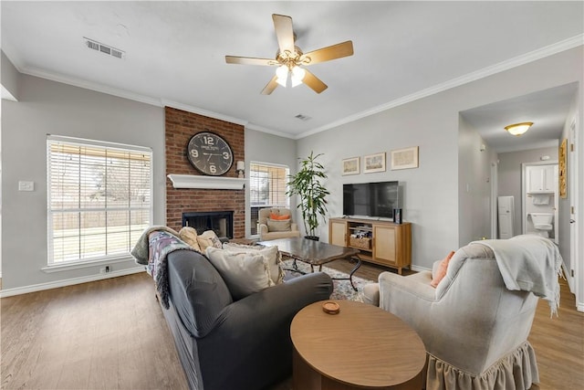 living area with plenty of natural light, wood finished floors, visible vents, and baseboards