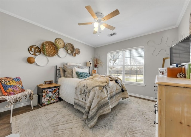 bedroom featuring baseboards, wood finished floors, visible vents, and crown molding