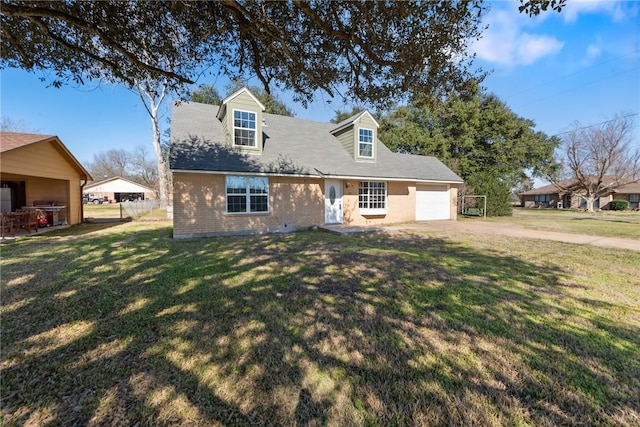 cape cod home with a garage, dirt driveway, brick siding, and a front yard