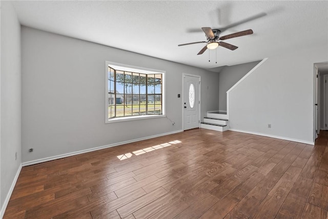 unfurnished living room featuring baseboards, stairway, and wood finished floors