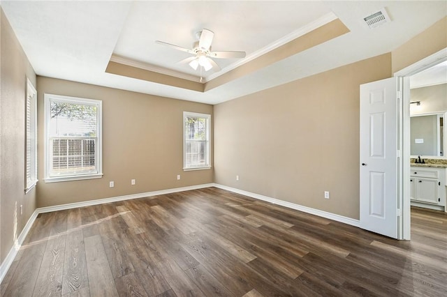 spare room with a tray ceiling, crown molding, ceiling fan, and dark hardwood / wood-style floors