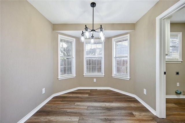 unfurnished dining area with dark wood-type flooring and an inviting chandelier