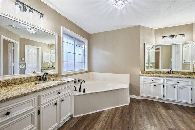 bathroom with a bathing tub, a chandelier, vanity, and wood-type flooring