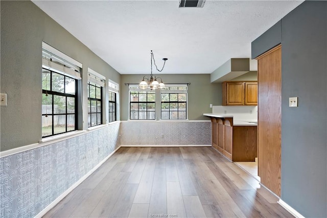2811 Arroyo Ct N, College Station, TX 77845 - unfurnished dining area with a chandelier, wood finished floors, healthy amount of natural light, wainscoting, and baseboards
