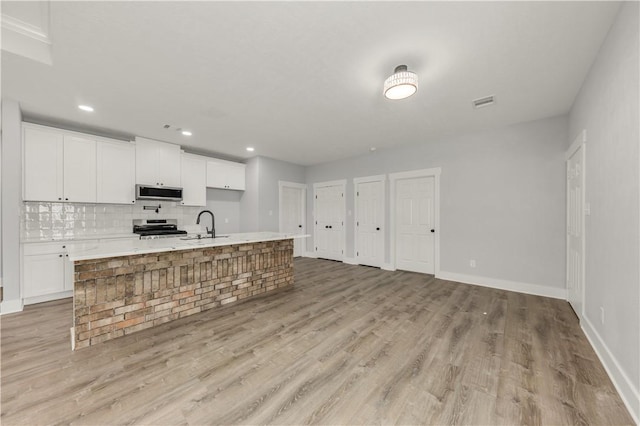 kitchen with white cabinetry, appliances with stainless steel finishes, sink, and an island with sink