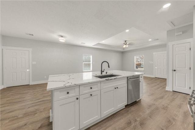 kitchen with sink, a tray ceiling, dishwasher, a kitchen island with sink, and white cabinets