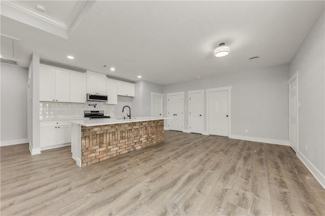 kitchen with white cabinetry, appliances with stainless steel finishes, sink, and a large island with sink