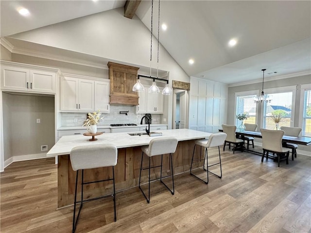 kitchen featuring white cabinets, sink, a large island with sink, and light hardwood / wood-style flooring