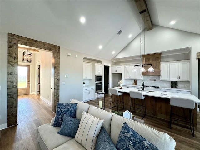 kitchen featuring a kitchen bar, appliances with stainless steel finishes, dark hardwood / wood-style flooring, a kitchen island with sink, and beam ceiling