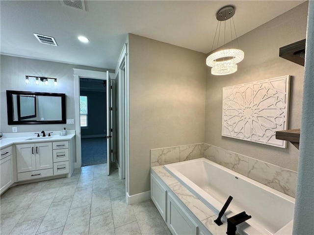 bathroom with a chandelier, vanity, and a washtub