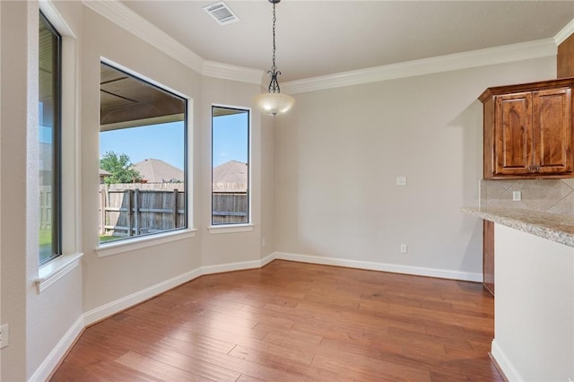 15613 Wood Brook Ln, College Station, TX 77845 - unfurnished dining area featuring plenty of natural light, light wood-style floors, and crown molding