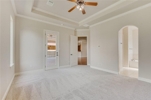 15613 Wood Brook Ln, College Station, TX 77845 - unfurnished bedroom featuring arched walkways, a tray ceiling, light carpet, crown molding, and ensuite bath