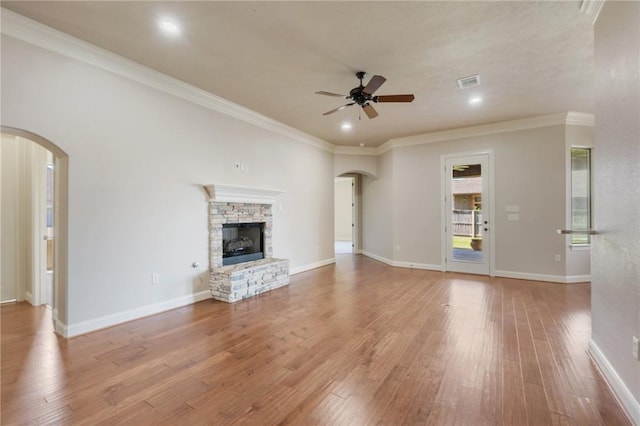 15613 Wood Brook Ln, College Station, TX 77845 - unfurnished living room featuring arched walkways, ceiling fan, light wood-type flooring, a fireplace, and ornamental molding