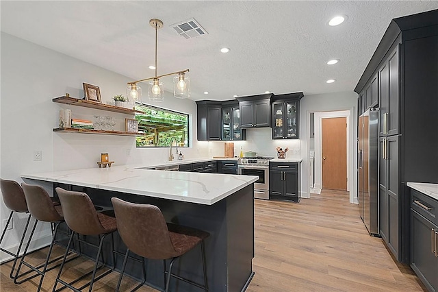 kitchen featuring stainless steel appliances, recessed lighting, a peninsula, visible vents, and glass insert cabinets