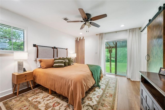 bedroom with visible vents, access to exterior, a barn door, recessed lighting, and light wood-style flooring
