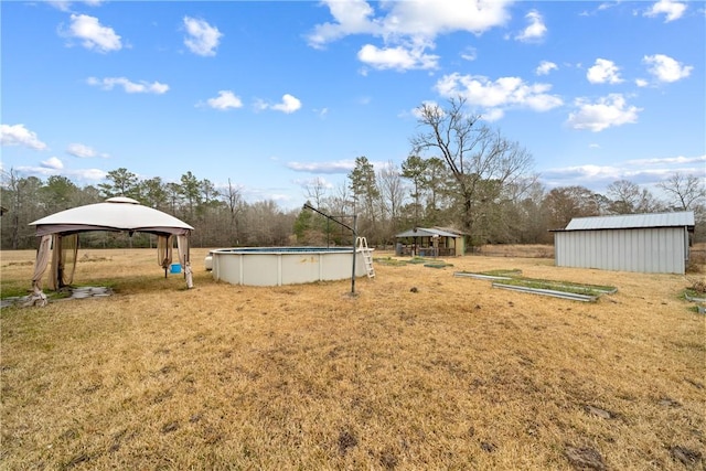 view of yard featuring a gazebo, an outdoor pool, and an outbuilding