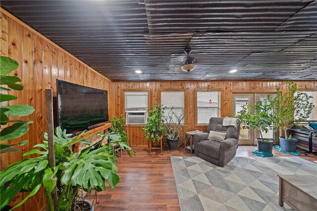 living room with wood walls, cooling unit, and wood finished floors