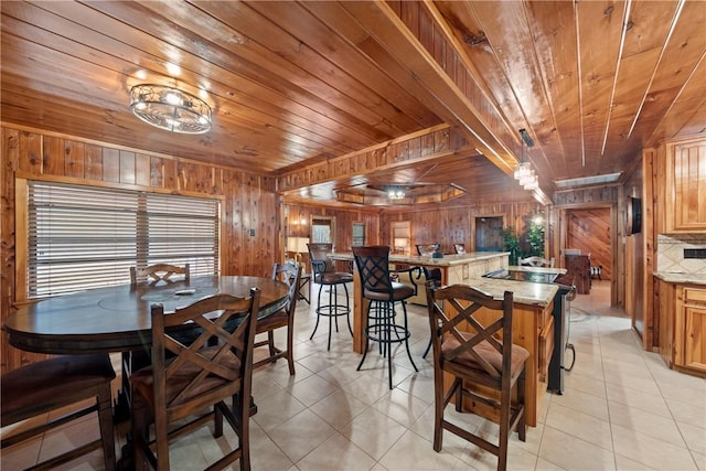 dining space featuring light tile patterned floors, wood walls, and wood ceiling