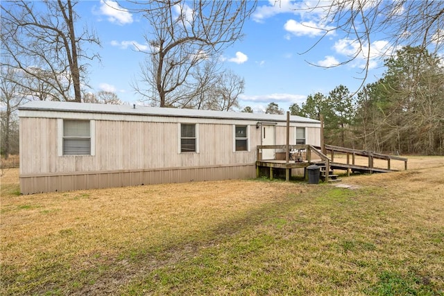 rear view of property featuring a wooden deck and a lawn