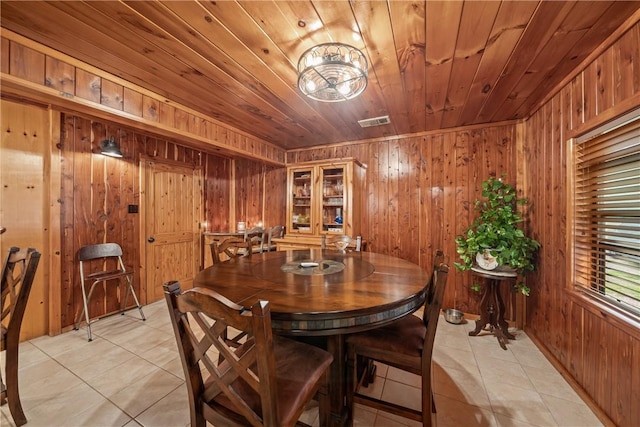 dining room with light tile patterned floors, visible vents, wooden walls, and wood ceiling