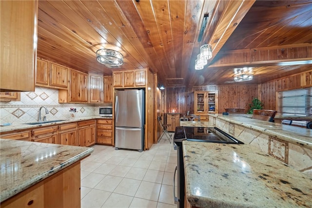 kitchen with tasteful backsplash, light stone countertops, light tile patterned flooring, stainless steel appliances, and a sink