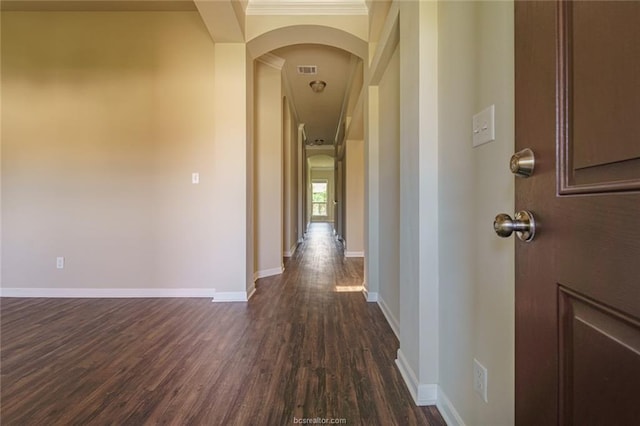 hall featuring arched walkways, dark wood finished floors, baseboards, and ornamental molding