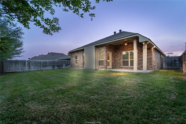 back of house at dusk with brick siding and a patio area