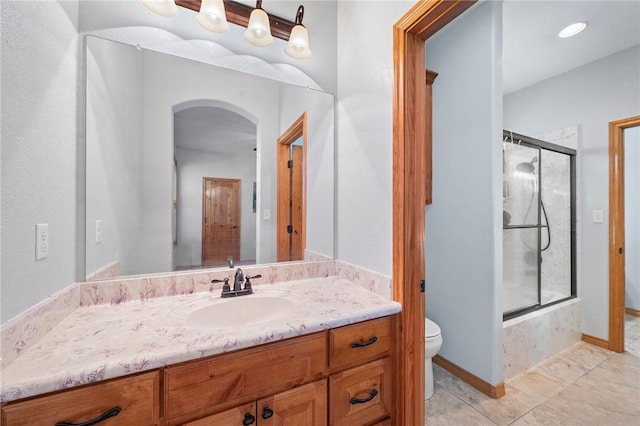 bathroom featuring a shower with door, vanity, and toilet