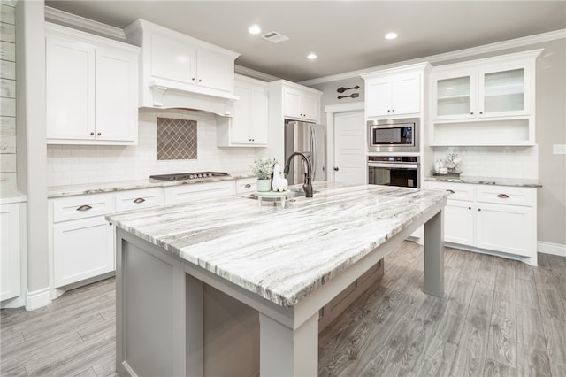 kitchen featuring a kitchen island with sink, white cabinets, and stainless steel appliances