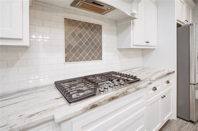 kitchen featuring white cabinetry, light wood-type flooring, backsplash, and appliances with stainless steel finishes