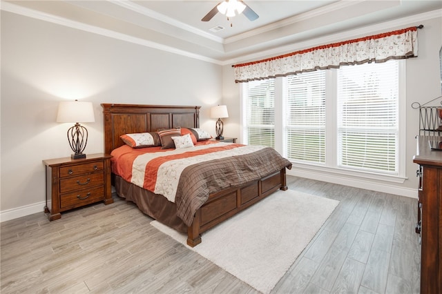 bedroom featuring ceiling fan, a raised ceiling, light wood-type flooring, and ornamental molding