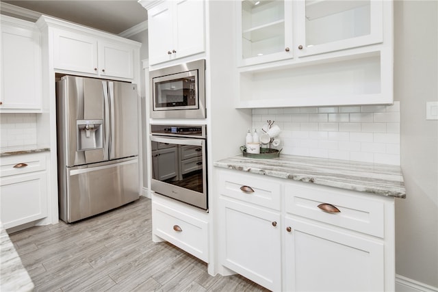 kitchen featuring appliances with stainless steel finishes, backsplash, light stone counters, light hardwood / wood-style flooring, and white cabinets