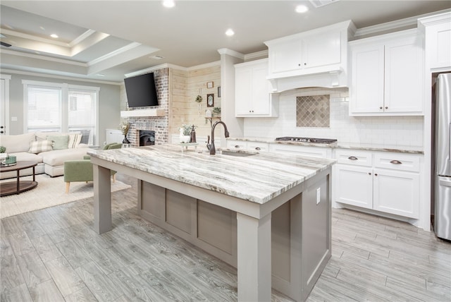 kitchen with white cabinetry, sink, and an island with sink