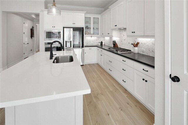 3609 Llano River Dr, College Station, TX 77845 - kitchen with appliances with stainless steel finishes, a sink, backsplash, light wood-style flooring, and white cabinetry