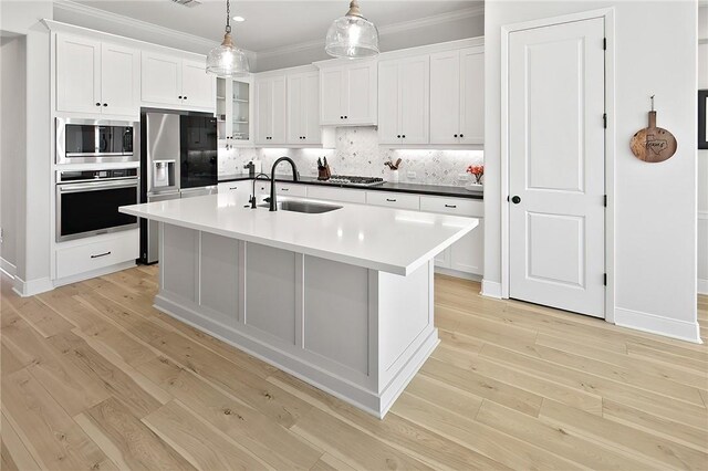 3609 Llano River Dr, College Station, TX 77845 - kitchen with stainless steel appliances, a sink, ornamental molding, light wood-style floors, and white cabinetry