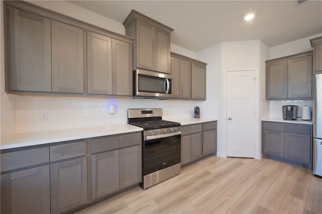 kitchen with light wood-type flooring, stainless steel appliances, and gray cabinetry