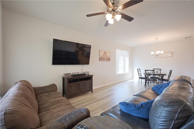 living room featuring ceiling fan with notable chandelier and light wood-type flooring