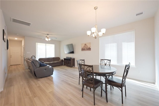 dining space with ceiling fan with notable chandelier and light wood-type flooring