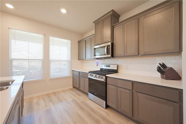 kitchen featuring backsplash, plenty of natural light, stainless steel appliances, and light hardwood / wood-style flooring