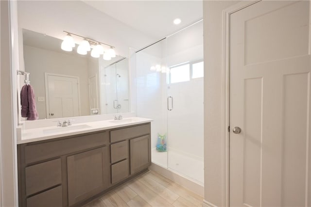 bathroom with hardwood / wood-style floors, vanity, and a shower with door