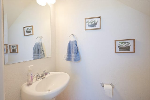 bathroom featuring lofted ceiling and sink